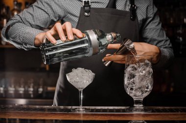 Alkollü içki kokteyl hazırlamak için bir banyo kullanarak bir bardak içine dökme barmen