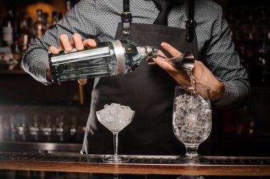 Alkollü içki kokteyl hazırlamak için bir banyo kullanarak bir bardak içine dökme barmenler eller