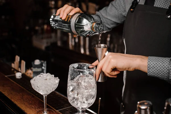 Barmans manos verter bebida alcohólica en un jigger para preparar un cóctel fresco — Foto de Stock