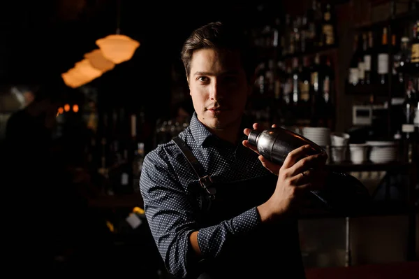 Bir shaker karanlık bir barda tutan yakışıklı barmen — Stok fotoğraf