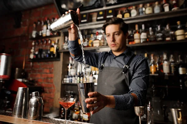Genç barmen bir metal cam alkollü içki başka içine dökme — Stok fotoğraf