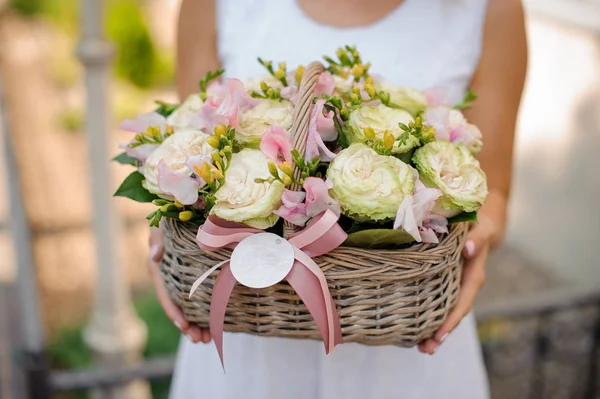 kadın bir hasır sepet gül ve ranunkulus dolu tutar