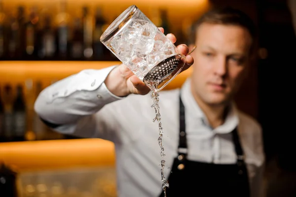 Barmann schenkt alkoholischen Cocktail mit Eis mit Sieb und Glas ein — Stockfoto