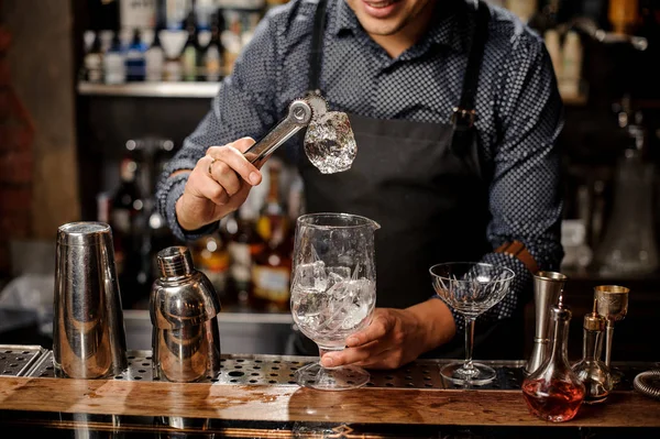 Barkeeper hält das Stück Eis mit der Pinzette — Stockfoto