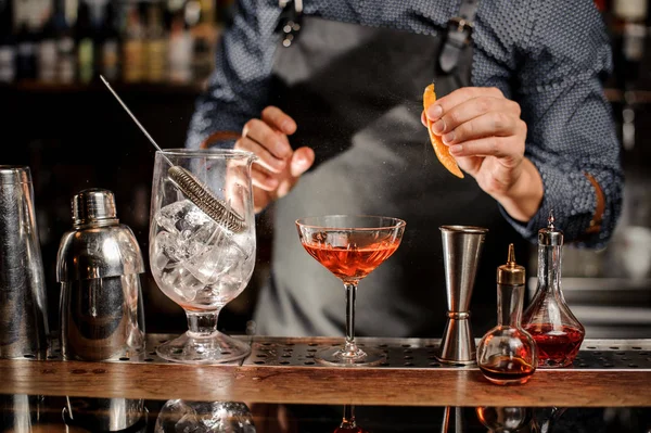Bartender vai pulverizar uma casca de laranja em copo de cocktail — Fotografia de Stock