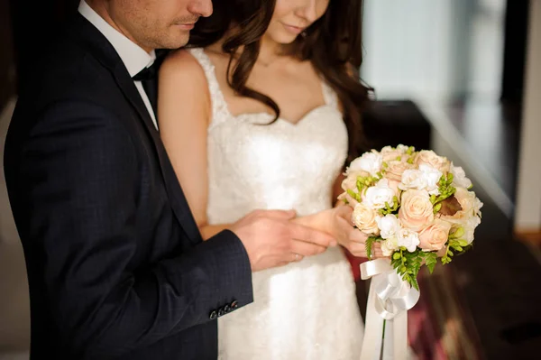 Noiva e noivo olhando juntos para o buquê de rosas — Fotografia de Stock