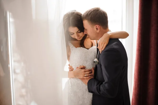 Bräutigam und Braut umarmen sich romantisch vor weißem Hintergrund — Stockfoto