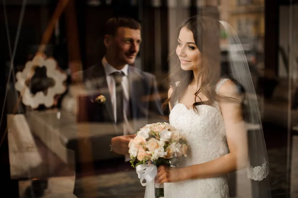 Bride looks out the window at the reflection of groom — Stock Photo, Image
