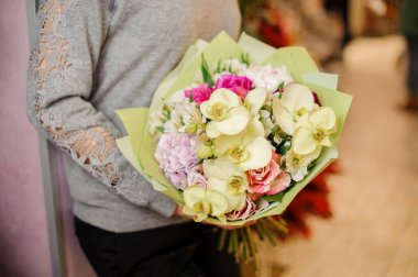 erkek bir buket bej orkide, pembe Gül ve yeşil paket mor ortanca tutar