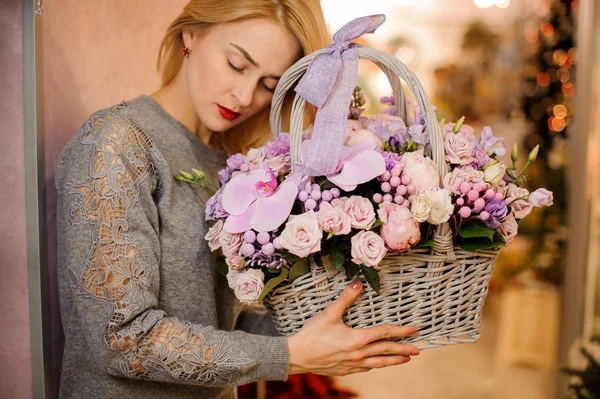 Blond dziewczyna posiada kosz fioletowe kwiaty róże i storczyki — Zdjęcie stockowe