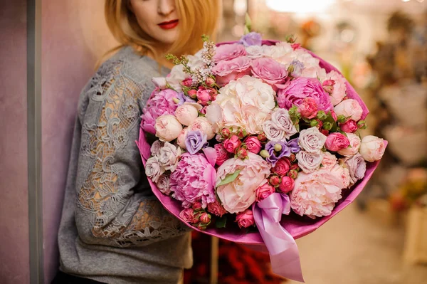 Elegante chica sonríe tiene un enorme ramo de diferentes flores de color rosa y púrpura — Foto de Stock
