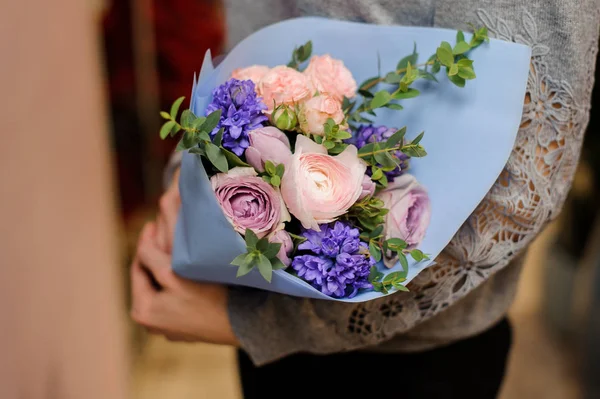 Perempuan memegang karangan bunga dengan mawar merah muda dan ungu berbentuk pion, eukaliptus dan mawar — Stok Foto