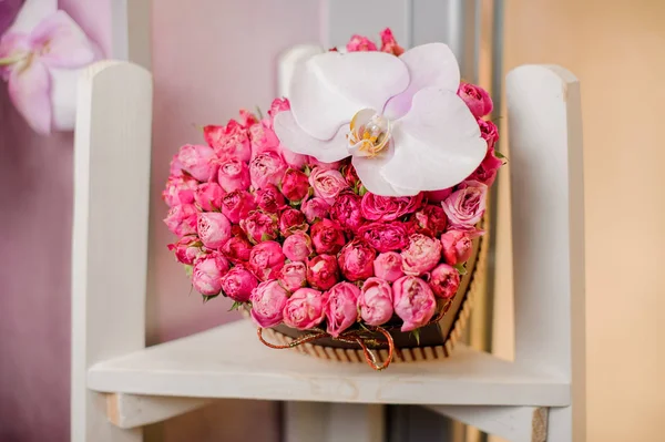 Bouquet en forme de coeur avec des roses et orchidée repose sur une chaise blanche — Photo