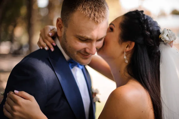 Lyckliga bruden kramar och kysser hennes leende brudgum — Stockfoto