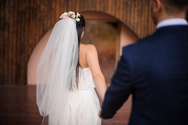 Brudgummen i en kostym efter sin vackra brud klädd i en vit klänning — Stockfoto