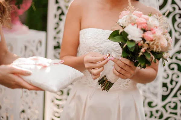 Novia vestida con un hermoso vestido de novia blanco sosteniendo un anillo — Foto de Stock