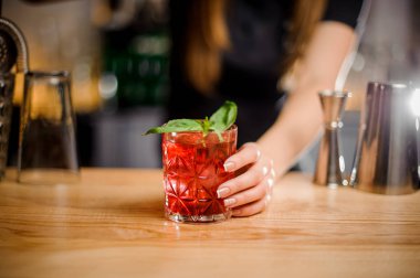 Barmen kırmızı renk bir kristal bardak bir kokteylle tutar