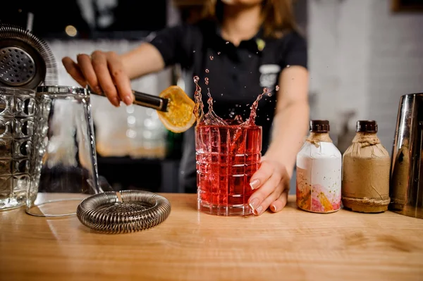 feat barmaid adding to the cocktail glass slice of lemon using tongs