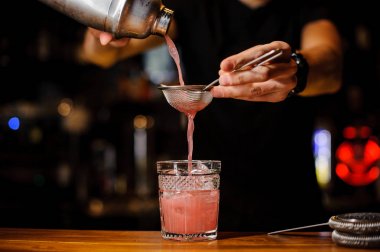 Barmen bir alkollü kokteyl shaker dan bir kristal cam içine dökülür.