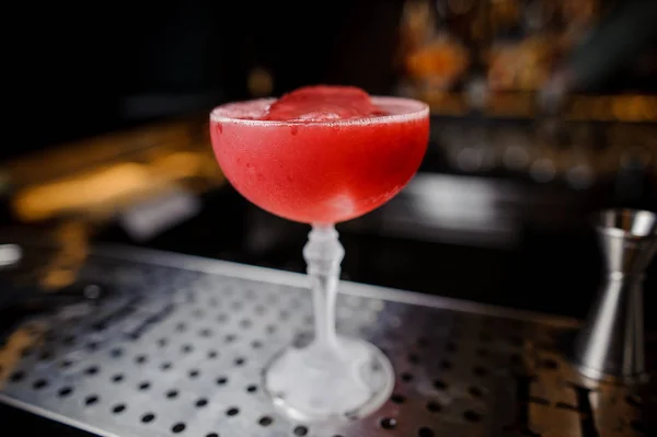 Cocktail alcolico rosso con ghiaccio rimane sul bancone del bar — Foto Stock