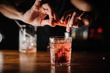 Barmen buz ile pembe renk alkollü kokteyl negroni hazırlanıyor