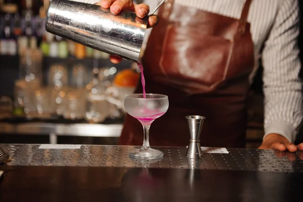 Kocsmáros kitölt egy acél shaker egy koktélospohárba egy lila színű alkoholt koktél — Stock Fotó