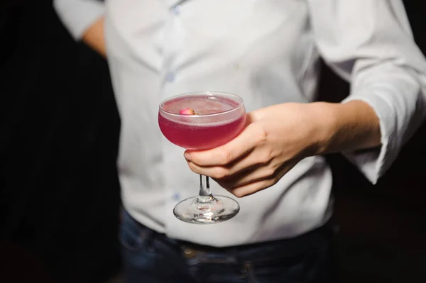 Chica sostiene cóctel alcohólico de color rosa con un capullo de rosa —  Fotos de Stock