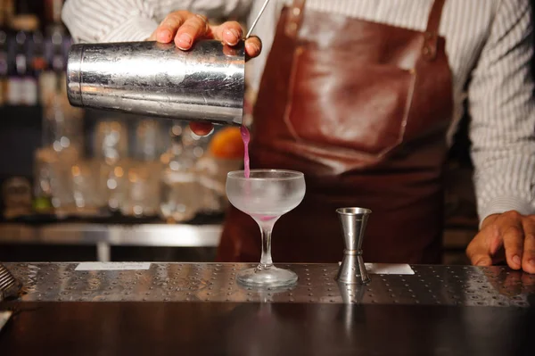 Barman dans un tablier brun verse d'un cocktail d'alcool shaker en acier — Photo