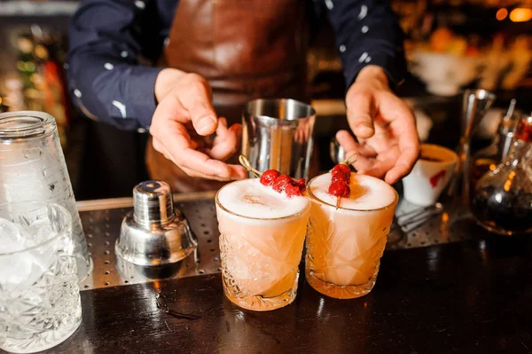 Barman preparou dois coquetéis alcoólicos Mistura azeda de cor âmbar com cerejas e gelo — Fotografia de Stock