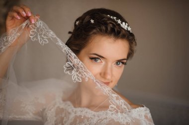 Beyaz elbise ve nazik bir makyaj gelin peçe elinde tutar