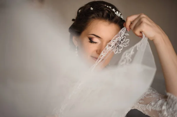 Bella sposa bruna copre le labbra con un velo bianco di pizzo — Foto Stock