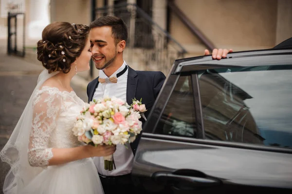 Bräutigam öffnet die Tür des Hochzeitswagens in der Absicht, die Braut zu küssen — Stockfoto