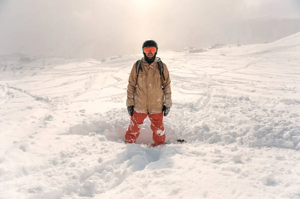 Αρσενικό γενειοφόρος snowboarder σε αθλητικά είδη και κράνος στέκεται στο th — Φωτογραφία Αρχείου