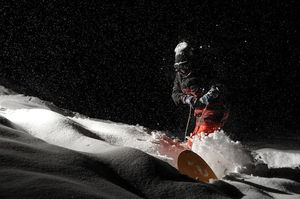Snowboarder in orangefarbener Sportbekleidung fährt mit dem sno — Stockfoto