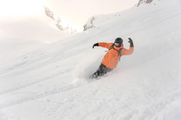 Mężczyzna snowboardzista w pomarańczowy sprawny i hełm jazda w dół — Zdjęcie stockowe