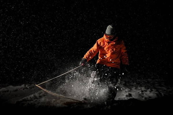 Professional male snowboarder riding on snow at night