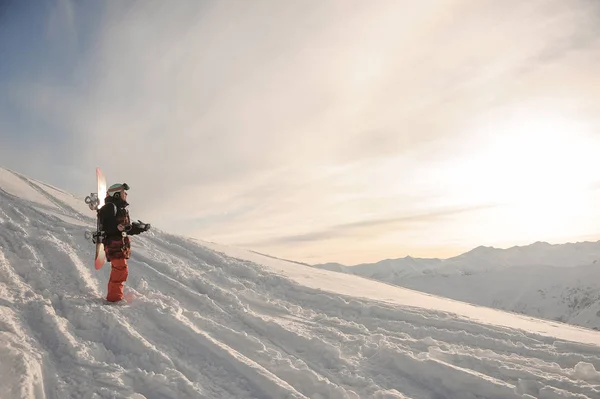 Молодой сноубордист стоит на горном снегу — стоковое фото