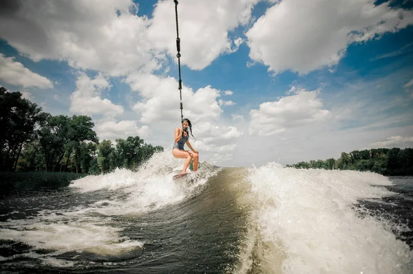 Lady släpas med wakeboard bakom en motorbåt av kabel — Stockfoto