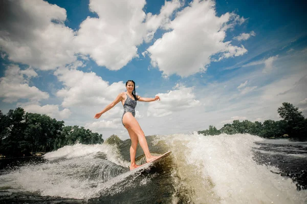 Morena mujer en traje de baño negro wakeboarding por el río —  Fotos de Stock
