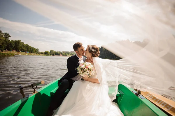 Glückliche und lächelnde Braut mit Bräutigam, der sich im Boot küsst — Stockfoto