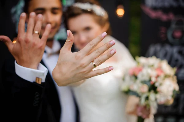 Noivo e noiva mostrando anéis de casamento em seus dedos — Fotografia de Stock