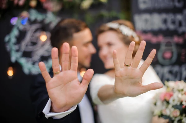 Lycklig brudgum och brud visar bröllop ringar på fingrarna — Stockfoto