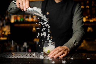 Kokteyl bardağına buz küpleri ekleyerek barmen. Maki süreci
