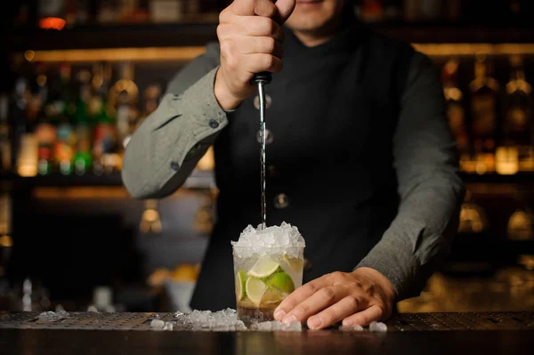 Barista versare cachaca nel bicchiere da cocktail. Processo di ma — Foto Stock