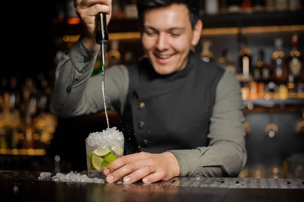 Barman sorrindo derramando cachaca na taça de coquetel. Processo — Fotografia de Stock