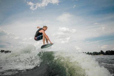 Genç wakesurf binici nehir dalgaları üzerinde atlama