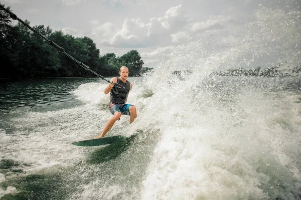 Ung och atletisk man wakesurfing i styrelsen mot himlen — Stockfoto