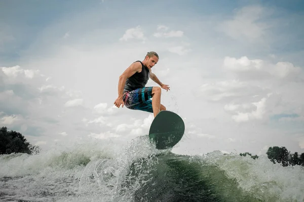 Fiatalok és a sportos srác wakesurfing a fedélzeten lefelé a folyón a — Stock Fotó