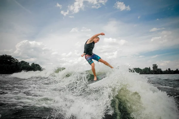 Atlético chico wakesurfing en el tablero por el río contra el — Foto de Stock