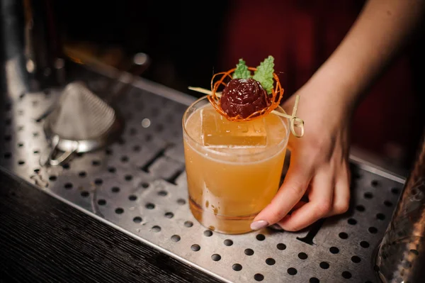 Frau hält ein Glas mit einem verzierten Cocktail in der Hand — Stockfoto
